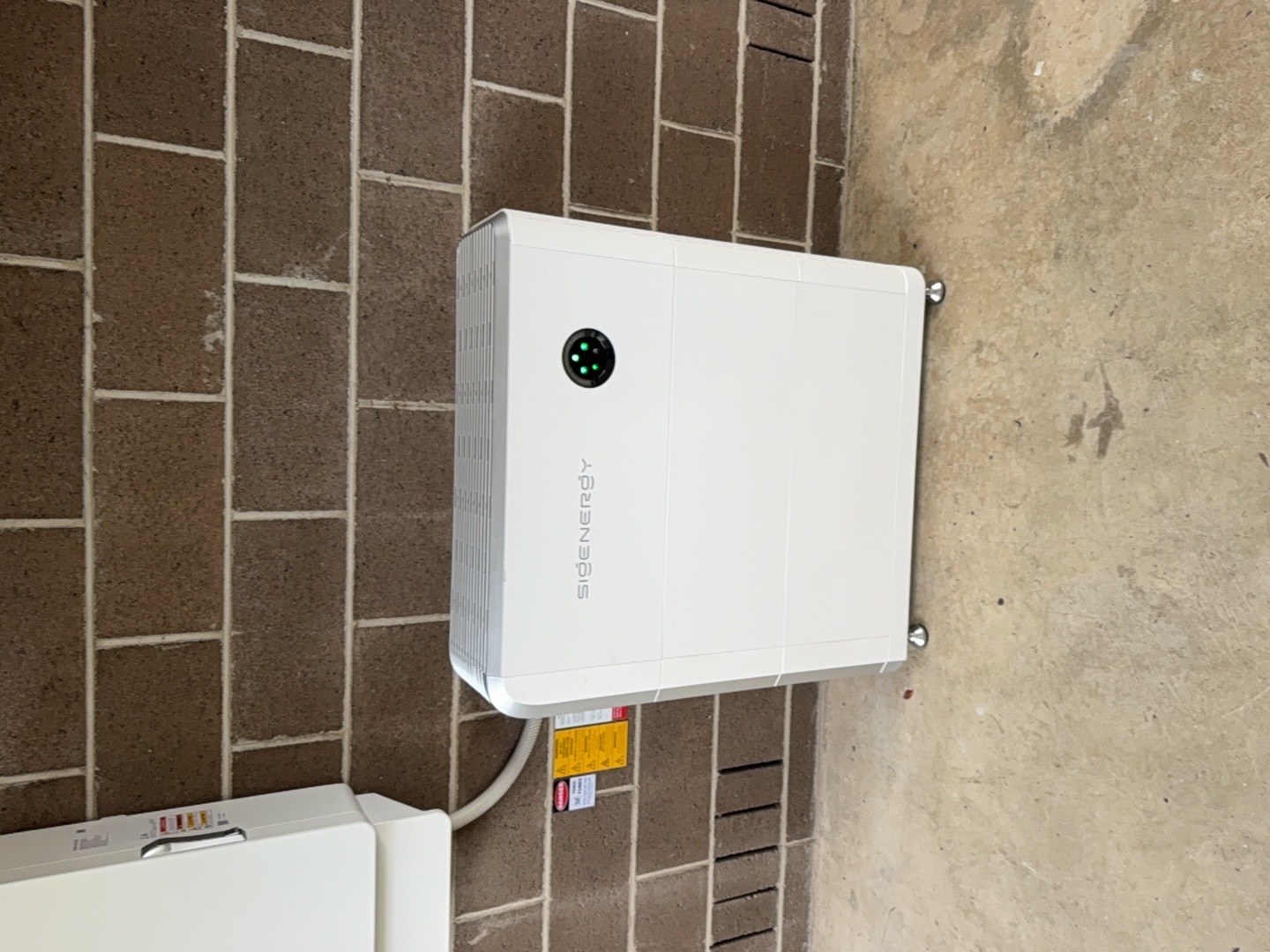 SigenEnergy battery storage unit on exterior brick wall