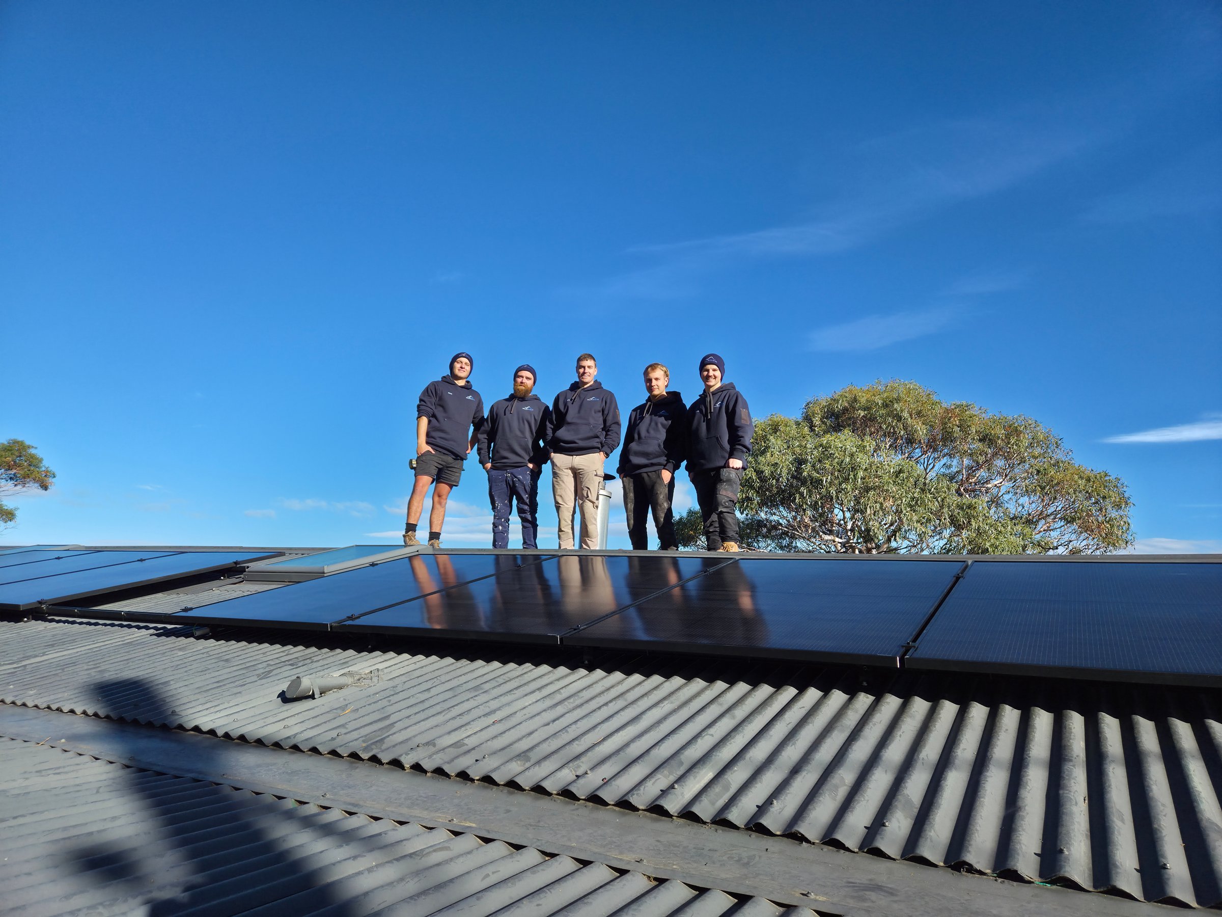 The Solar Coaster crew standing on a freshly installed solar panel roof